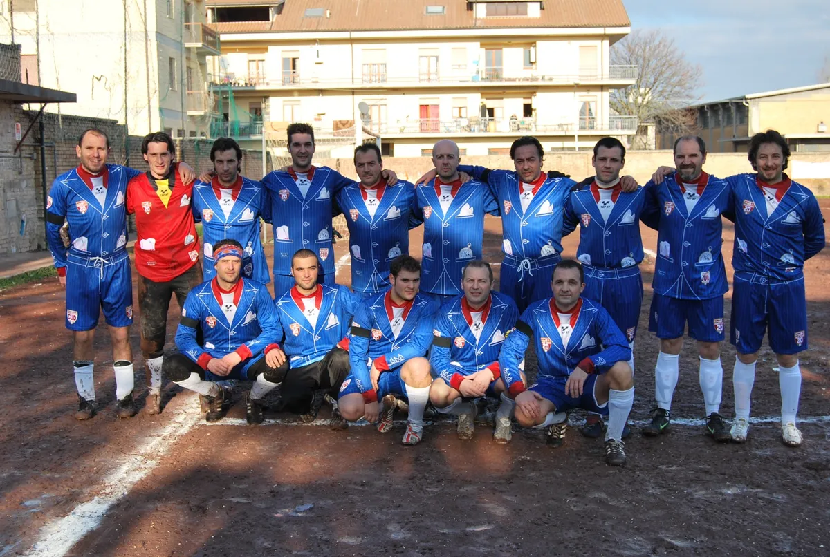 Foto di squadra in maglia blu a righe su un campo in terra.