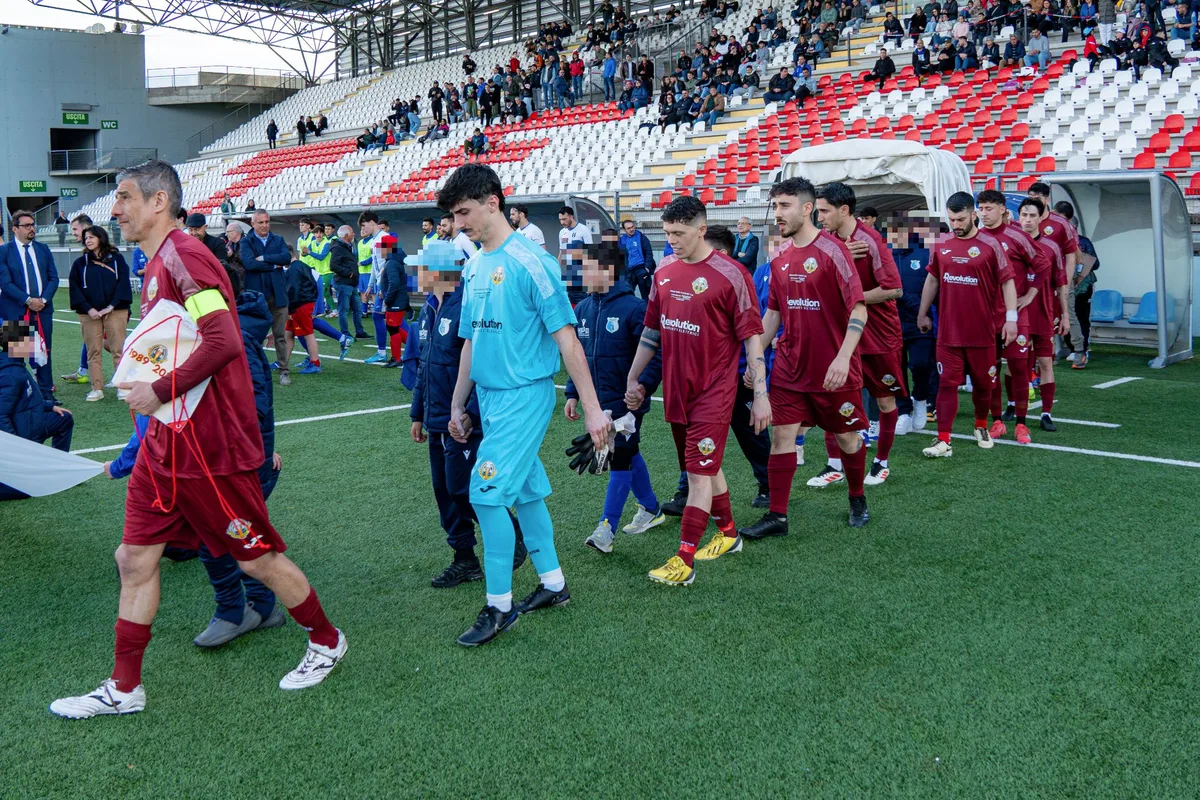 Le squadre entrano in campo in fila, accompagnate dai bambini, davanti alle tribune.